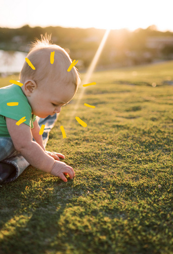 Baby playing i grass with sunshine